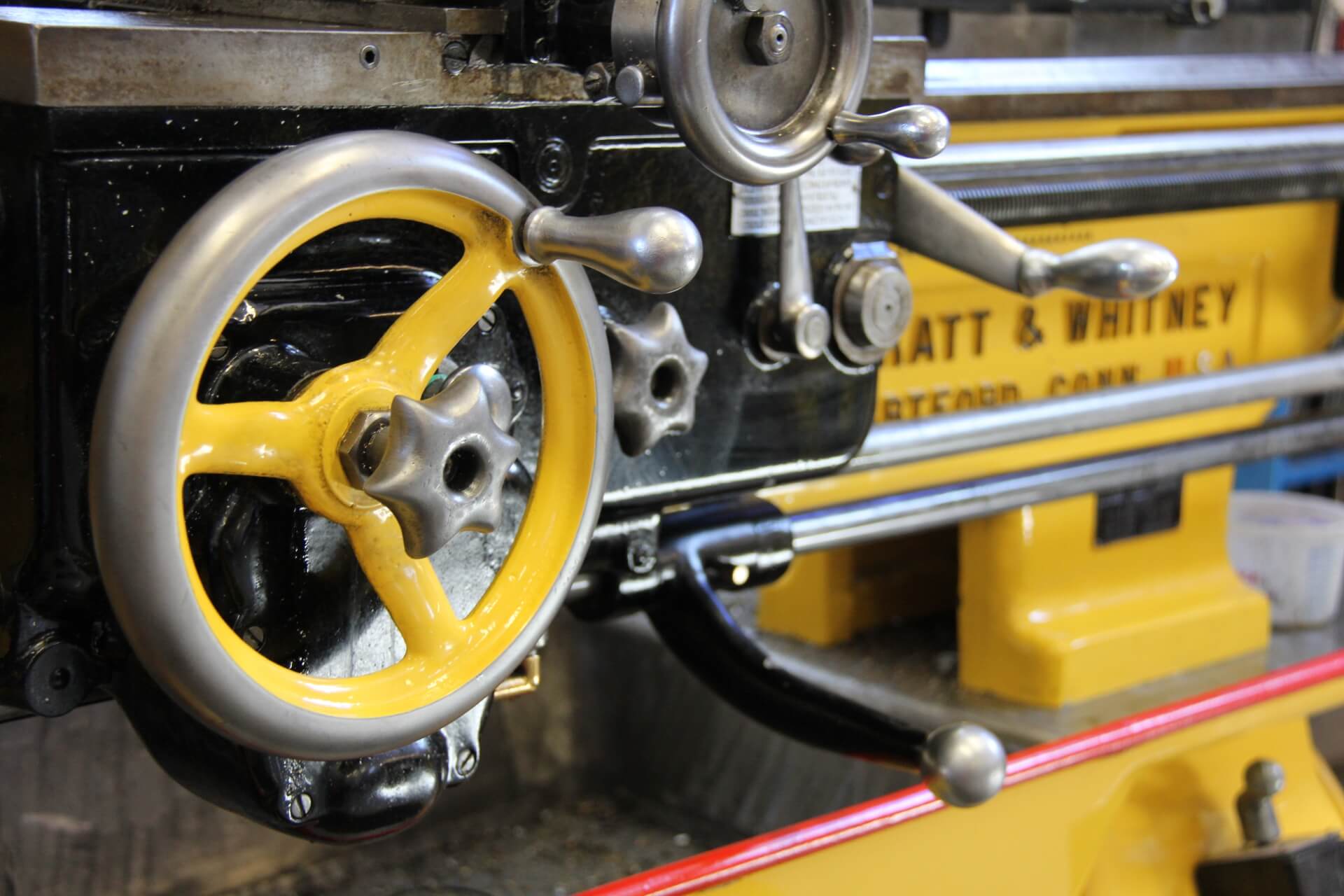 Close-up of a yellow machine tool in the Pumphrey and Co. workshop